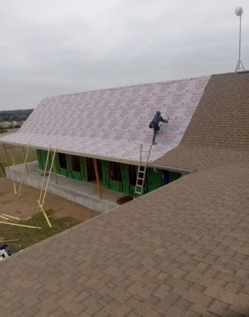 Worker preparing underlayment for a metal roof installation in Upper